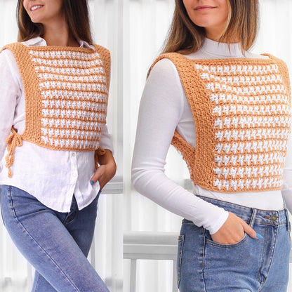 May include: A white and orange crochet top with a gingham pattern. The top is sleeveless and has a square neckline. The model is wearing the top with blue jeans.