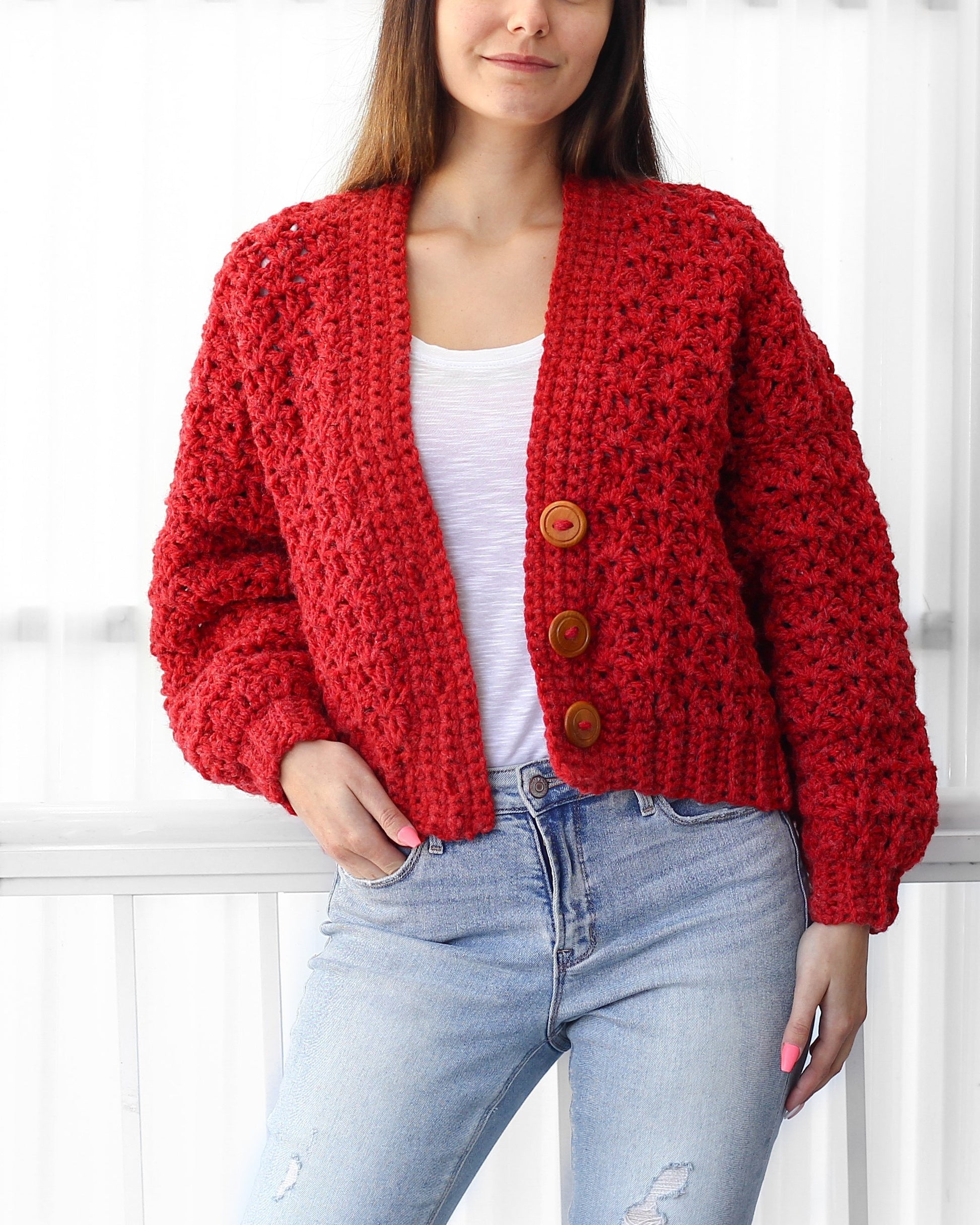 May include: A red crocheted cardigan with a button closure. The cardigan has a relaxed fit and is cropped at the waist.