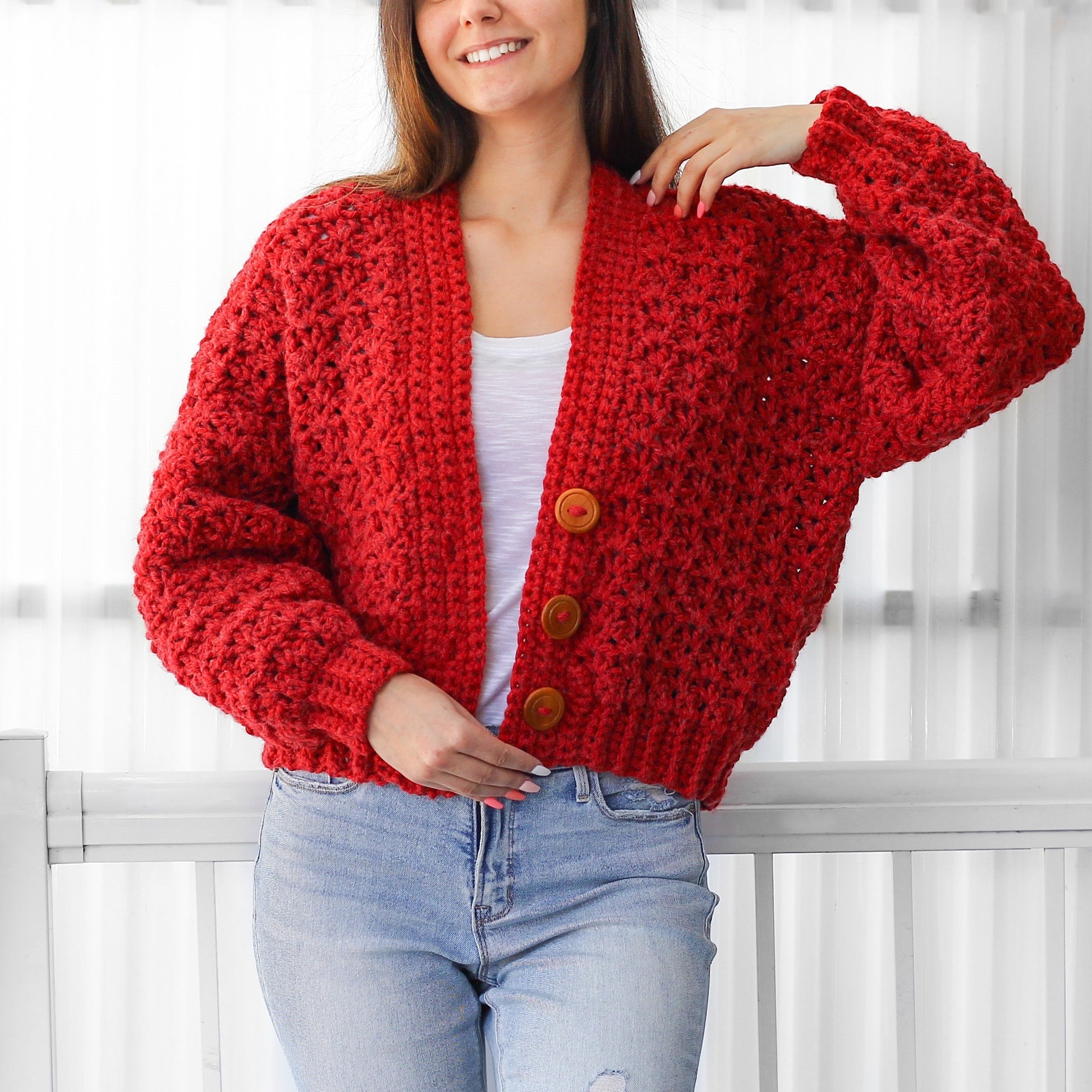 May include: A red crocheted cardigan with a button closure. The cardigan has a relaxed fit and a slightly cropped length.