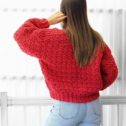 May include: A red crocheted sweater with a loose fit and long sleeves. The sweater is made with a textured stitch and has a relaxed, casual style.