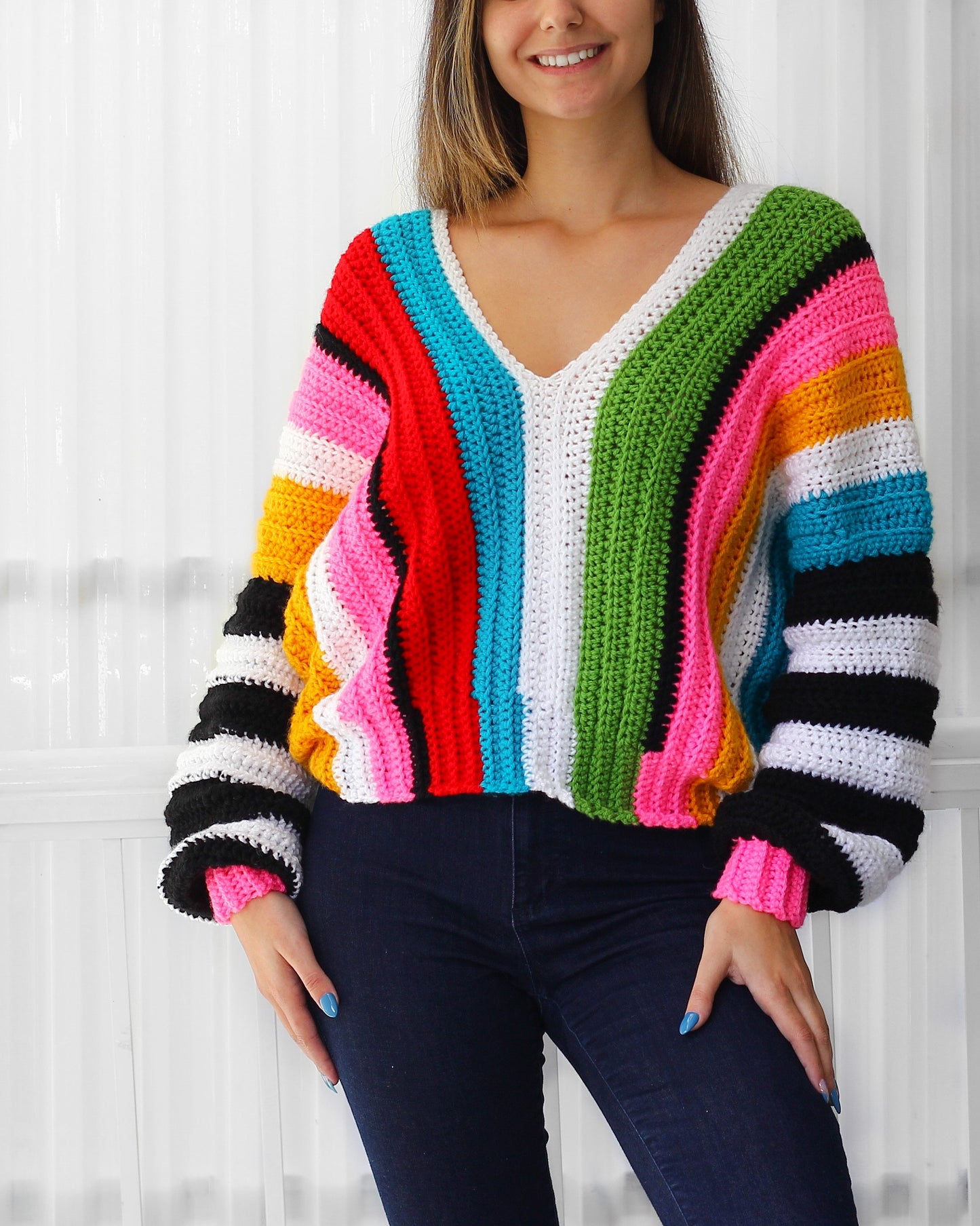 May include: A colorful striped crochet sweater with a V-neck and long sleeves. The sweater is made with a variety of colors, including red, orange, yellow, green, blue, and pink.