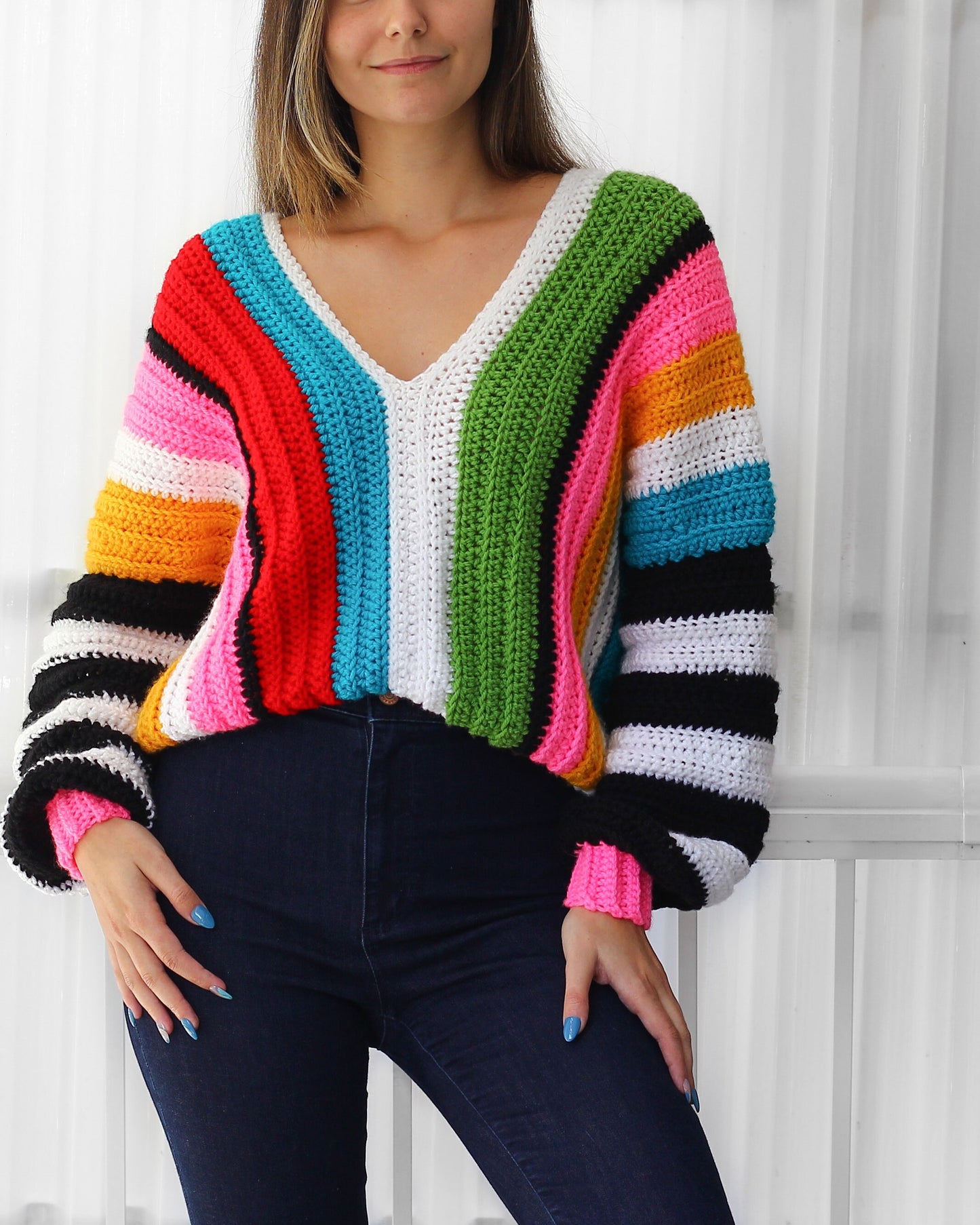 May include: A colorful striped crochet sweater with long sleeves and a V-neck. The sweater is made with a variety of colors, including red, orange, yellow, green, blue, and white.