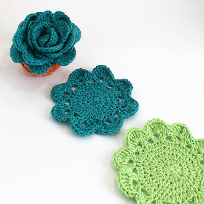 May include: Three crocheted coasters in the shape of flowers. The coasters are teal, green, and a light shade of green.