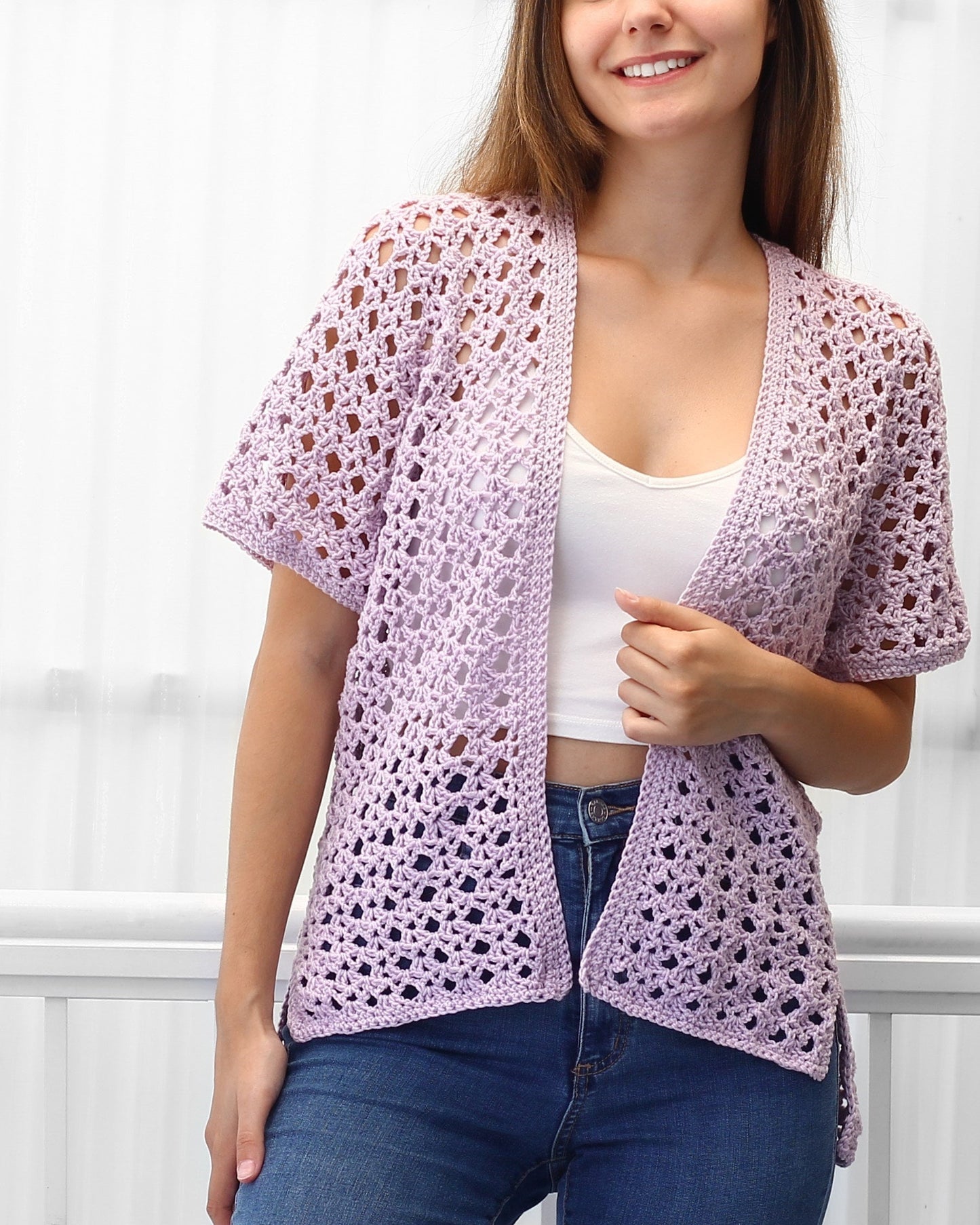 May include: A light purple crochet cardigan with a V-neck and short sleeves. The cardigan is open in the front and has a loose fit.