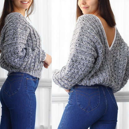 May include: A gray and white crochet sweater with a low back and a loose fit. The sweater is shown on a model wearing blue jeans.