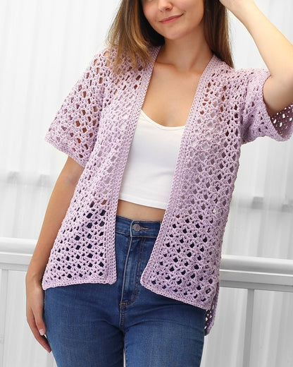 May include: A light purple crochet cardigan with a loose fit and short sleeves. The cardigan is open in the front and has a delicate, lacy pattern.