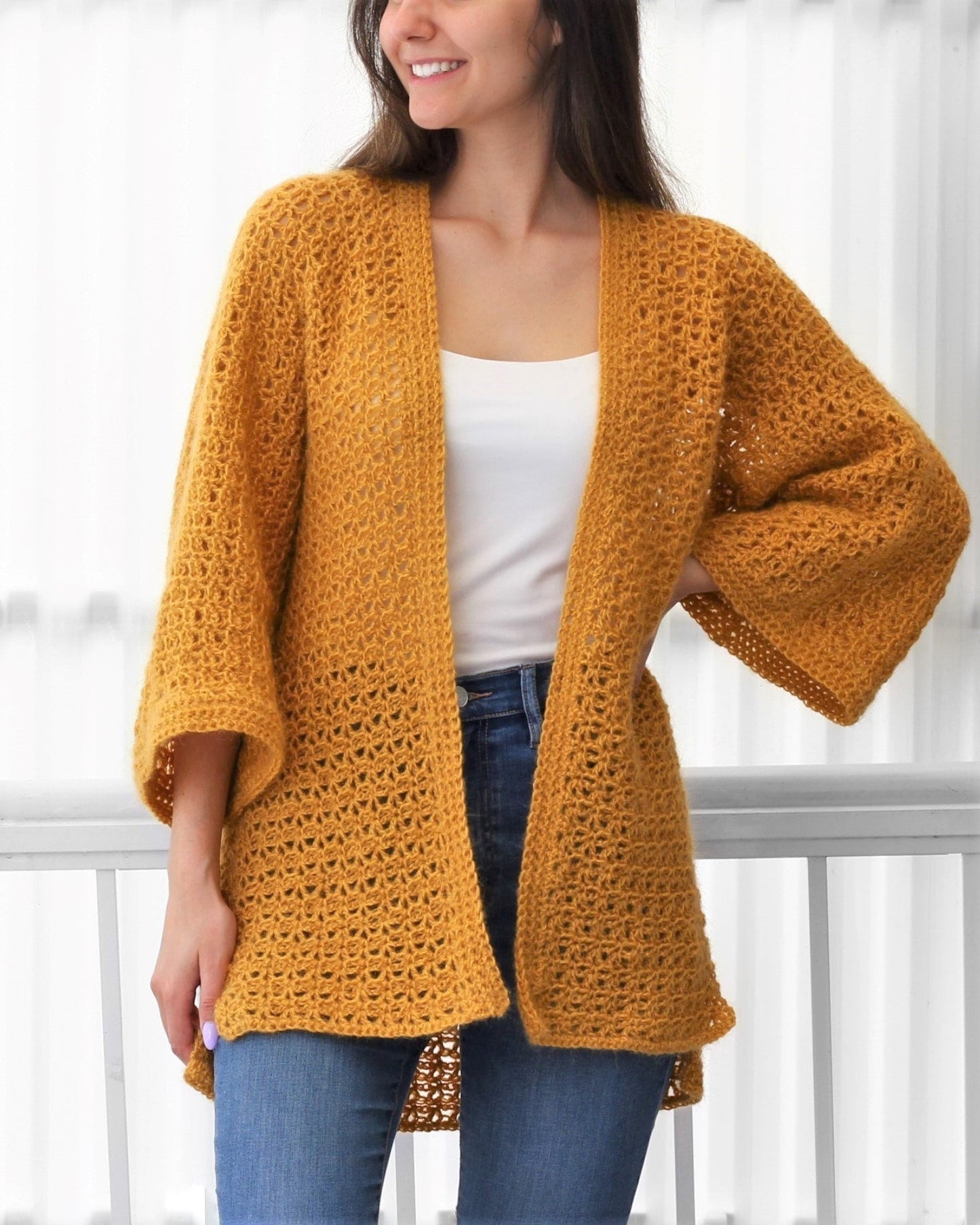 May include: A mustard yellow crochet cardigan with a loose fit and long sleeves. The cardigan is open in the front and has a simple, elegant design.