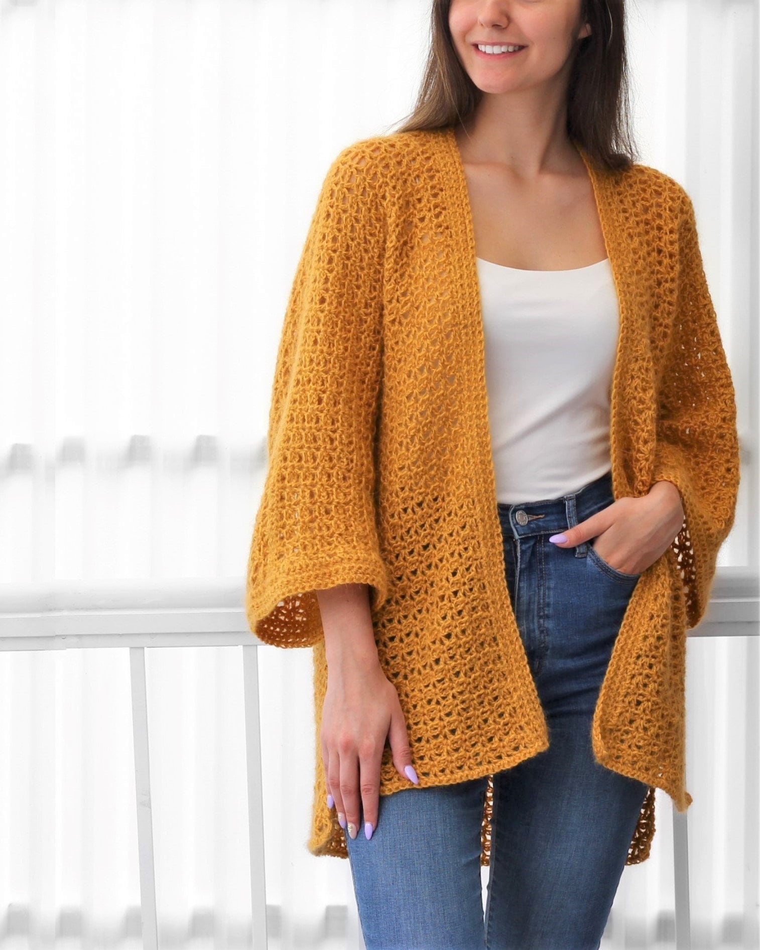 May include: A mustard yellow crochet cardigan with a loose fit and long sleeves. The cardigan is open in the front and has a simple stitch pattern.