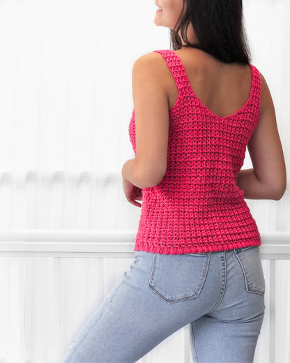 May include: A pink crocheted tank top with a v-neckline. The tank top is worn with light blue jeans.