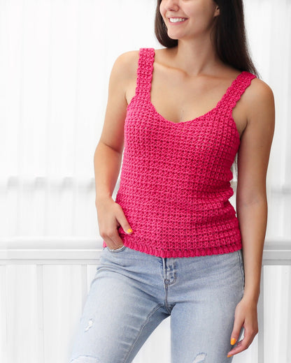 May include: A pink crochet tank top with a v-neck and thin straps. The top is made with a simple stitch pattern and has a relaxed fit.