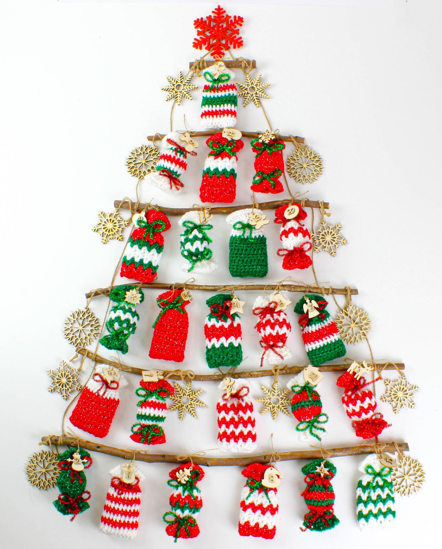 May include: A Christmas tree made of twigs with crocheted candy cane ornaments hanging from each branch. The ornaments are red, white, and green and have a snowflake design. There are wooden snowflakes hanging from the branches as well.