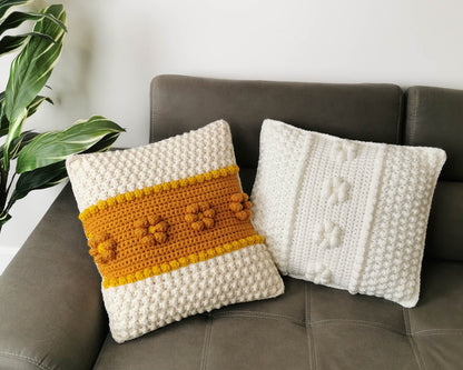 May include: Two crocheted throw pillows, one with a white background and a yellow stripe with raised flower accents, and the other with a white background and raised white dots.