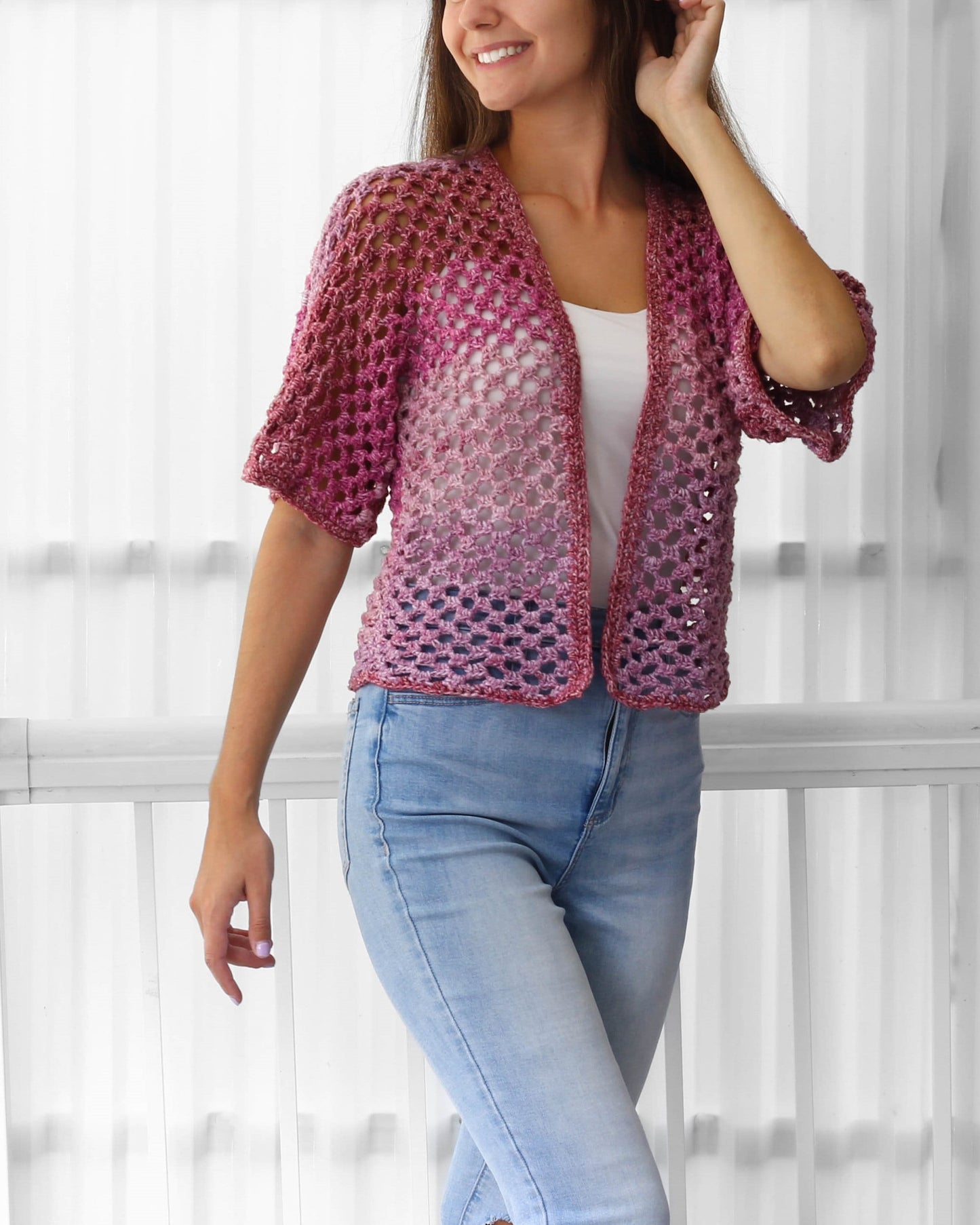 May include: A pink and purple ombre crochet cardigan with a loose fit and short sleeves. The cardigan is open in the front and has a delicate stitch pattern.