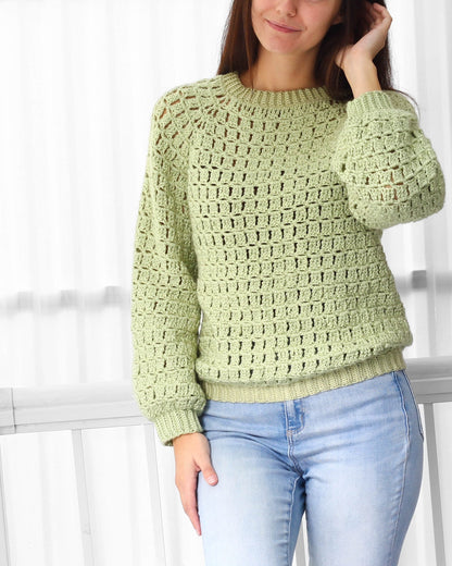 May include: A light green crochet sweater with a round neckline and long sleeves. The sweater has a loose fit and a textured stitch pattern.