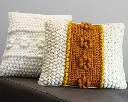 May include: Two crocheted throw pillows, one white with a textured surface and the other white with a yellow and brown stripe and textured surface.