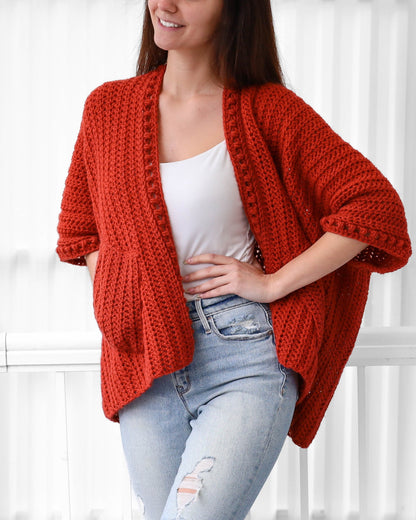 May include: A red crocheted cardigan with a loose fit and pockets. The cardigan has a V-neck and is made with a textured stitch.