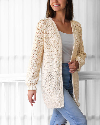 May include: A cream-colored crocheted cardigan with a long, open front and long sleeves. The cardigan is made with a delicate stitch pattern and has a relaxed fit.