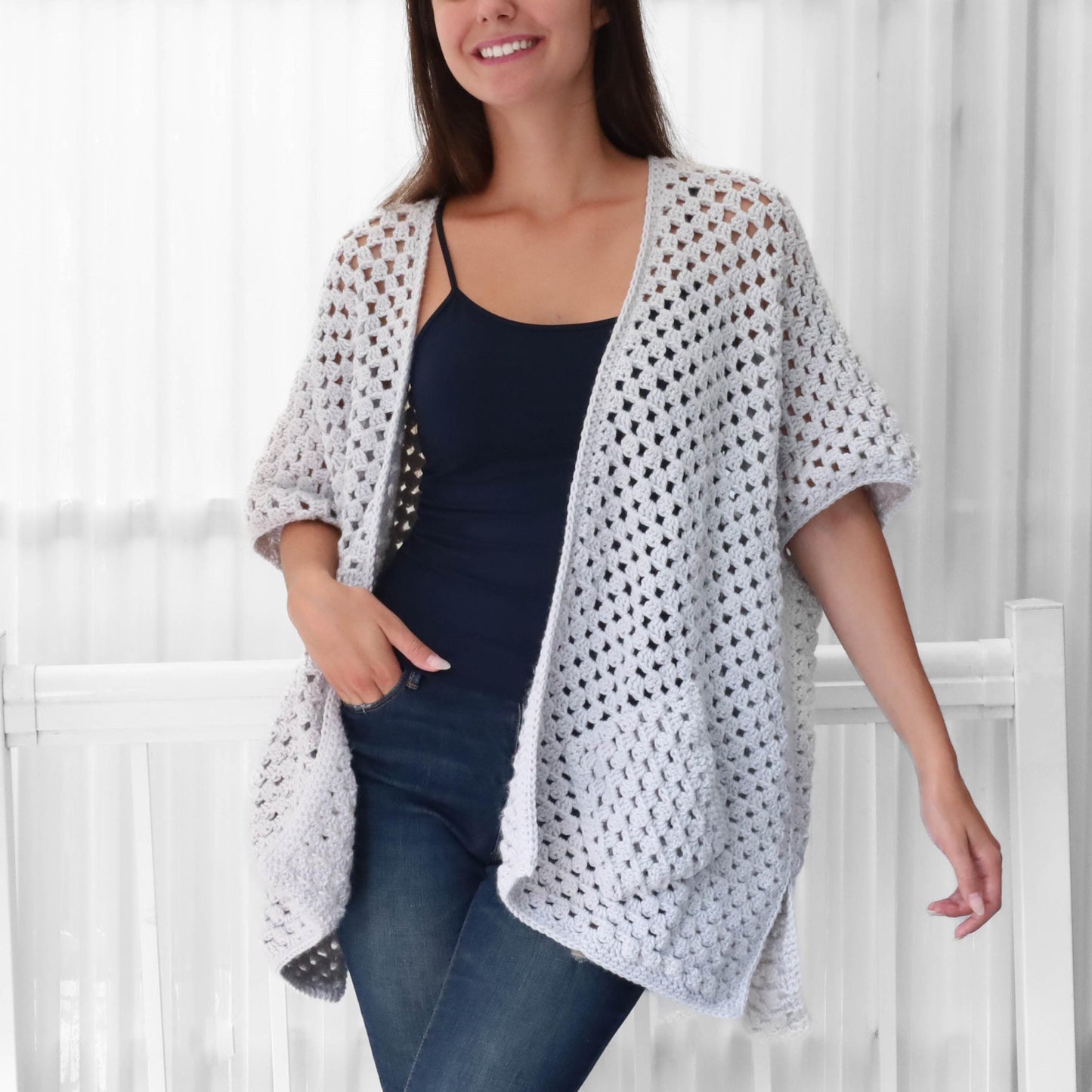 May include: A light gray crochet cardigan with a loose fit and short sleeves. The cardigan has a square stitch pattern and a pocket on the front.
