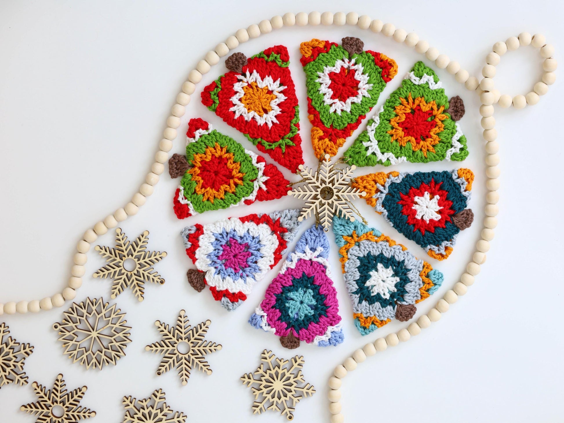 May include: A collection of crocheted Christmas tree ornaments in various colors and patterns, including red, green, blue, and white. The ornaments are arranged in a circle around a wooden bead garland.