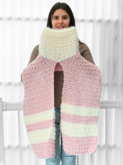 May include: A pink and white striped crocheted scarf with a fluffy texture. The scarf is long and wide, and it is held up by a person.