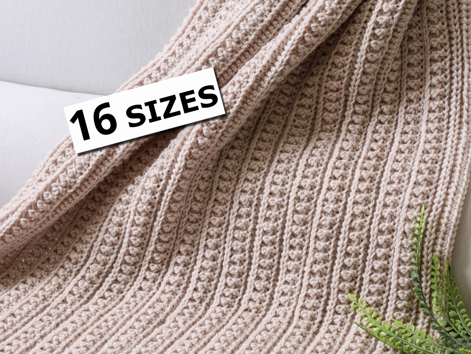 May include: A light beige crocheted blanket featuring a repeating vertical ribbed texture with small raised bobble stitches. A white rectangular label with the black text 16 SIZES is positioned on the upper left side of the fabric.