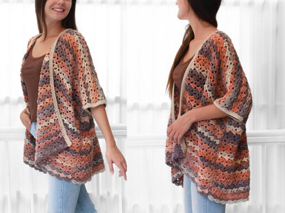 May include: A handmade, open-front crochet cardigan in shades of peach, gray, and cream. The short-sleeved garment features a geometric pattern and a neutral border. The cardigan is worn over a brown top and blue jeans.