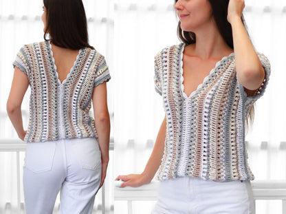 May include: A short-sleeved, V-neck crochet top in a neutral color palette of white, gray, and brown. The top features a scalloped edge along the neckline and sleeves. The open weave design is visible.
