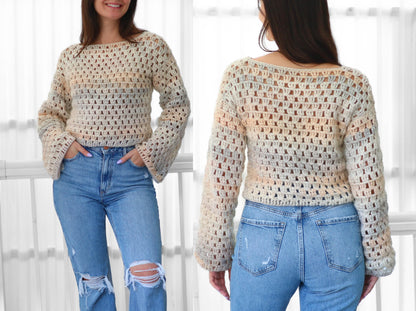 May include: A cream-colored, open-weave crochet sweater with long, flared sleeves. The sweater has a scoop neckline and a subtle color gradient of peach, blue, and gray. The person is wearing light blue ripped jeans.