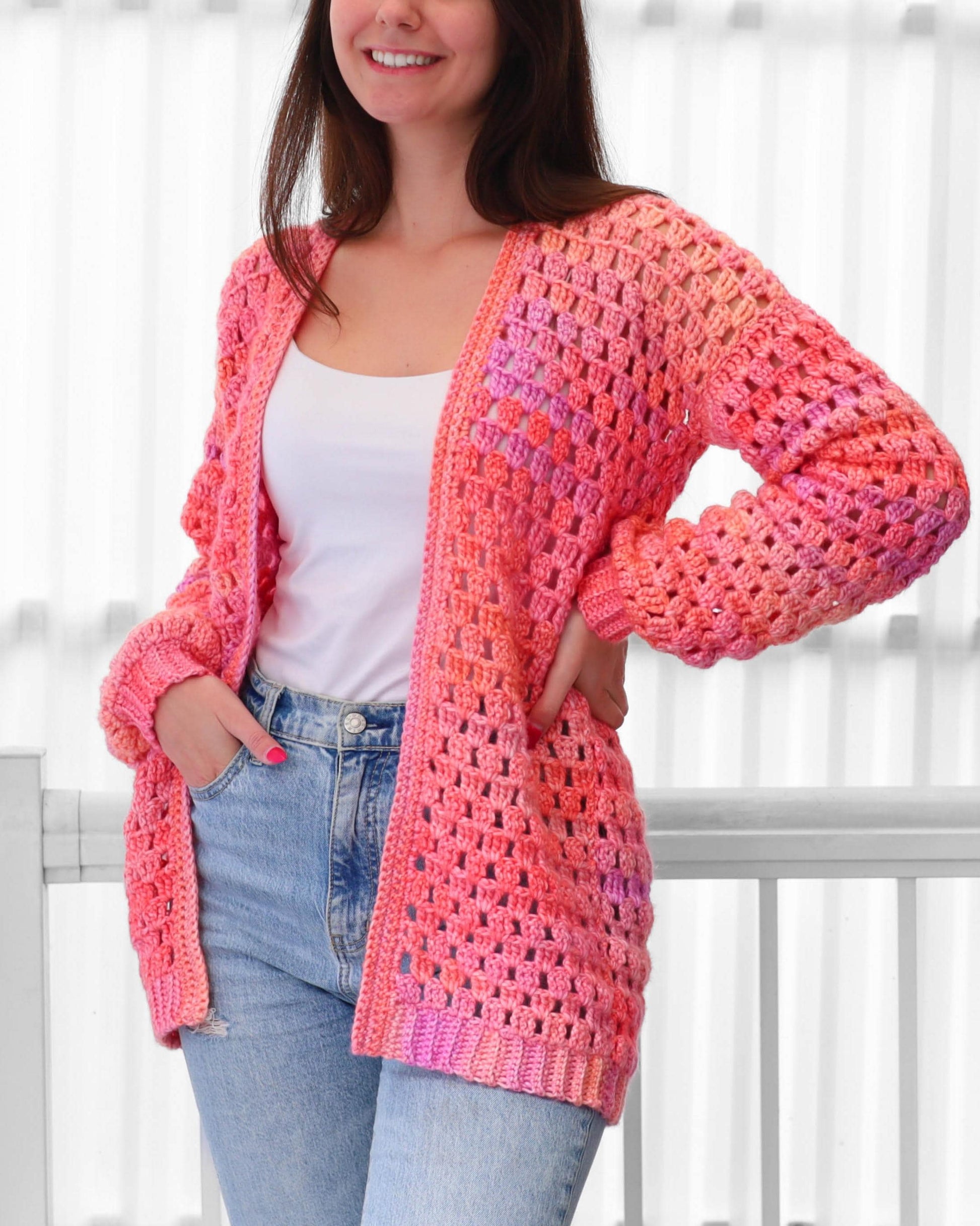 May include: A vibrant, open-front crochet cardigan in shades of pink and orange. The handmade garment features a loose, open weave design with long sleeves. The cardigan is a stylish, comfortable piece for layering.