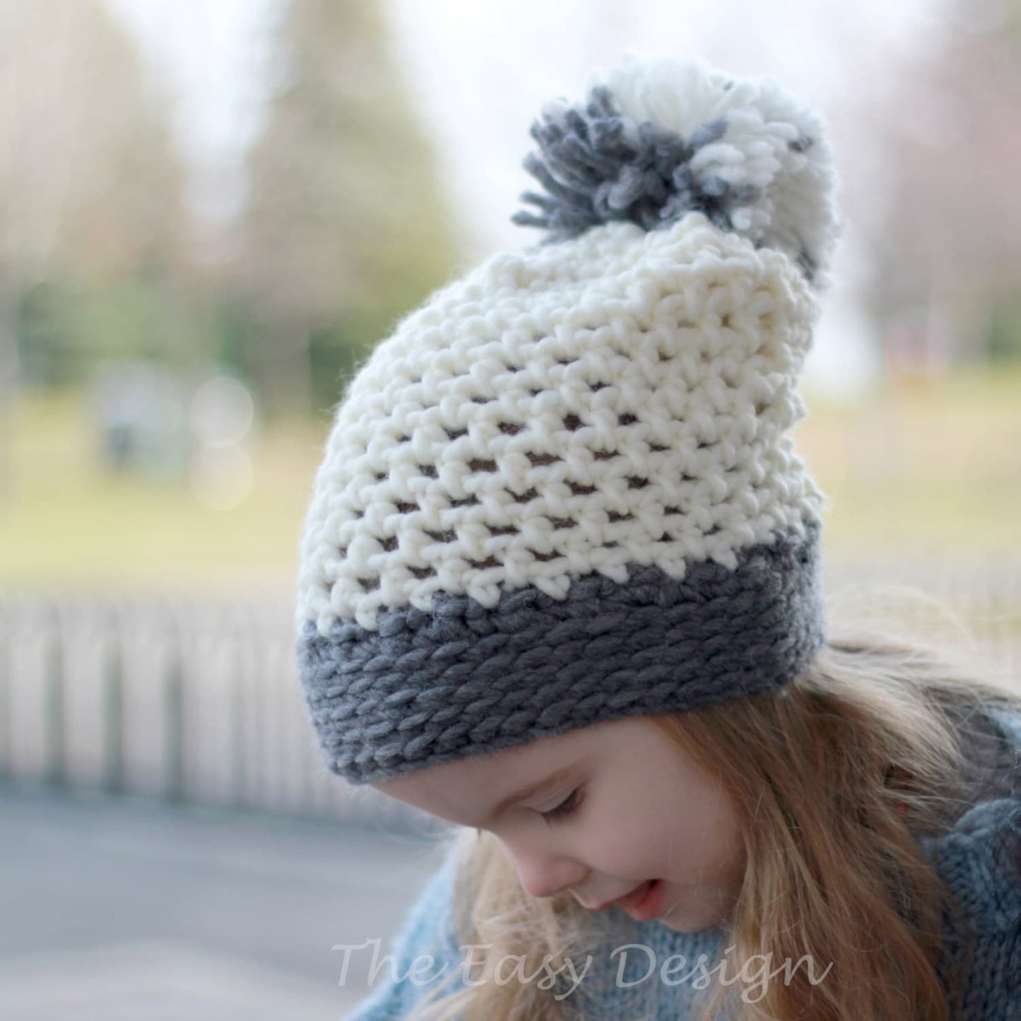May include: A white and gray crocheted beanie with a white and gray pom pom on top. The beanie has a white top and a gray bottom.