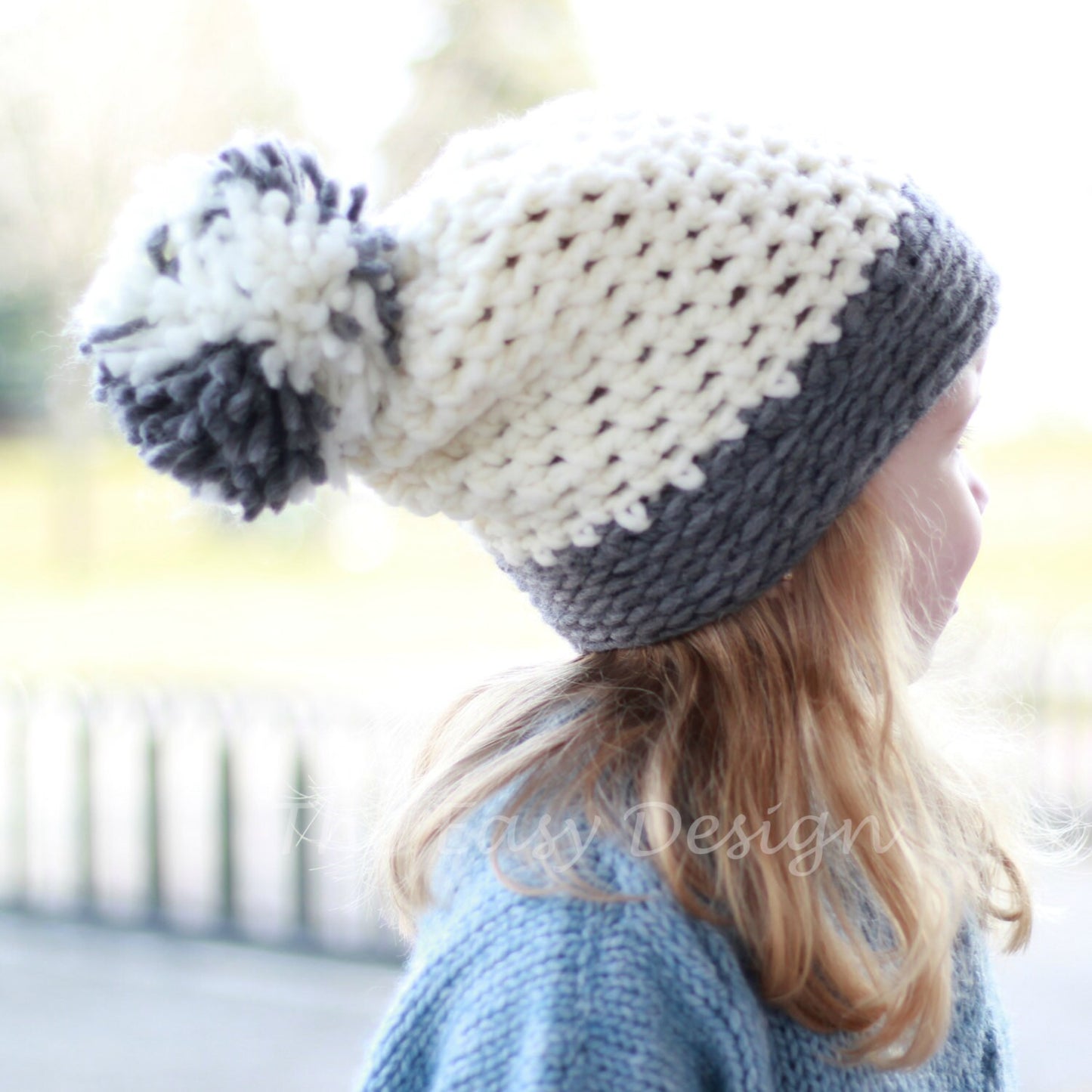 May include: A white and gray knitted beanie with a white pom pom. The beanie is made with a chunky yarn and has a simple design.